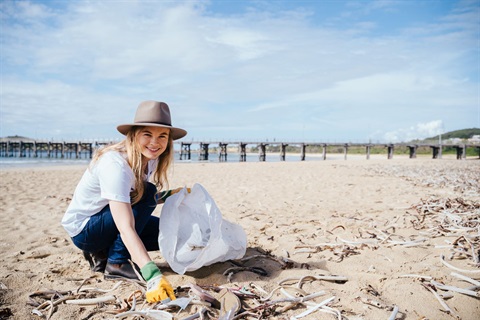 Image of a woman picking up beach litter